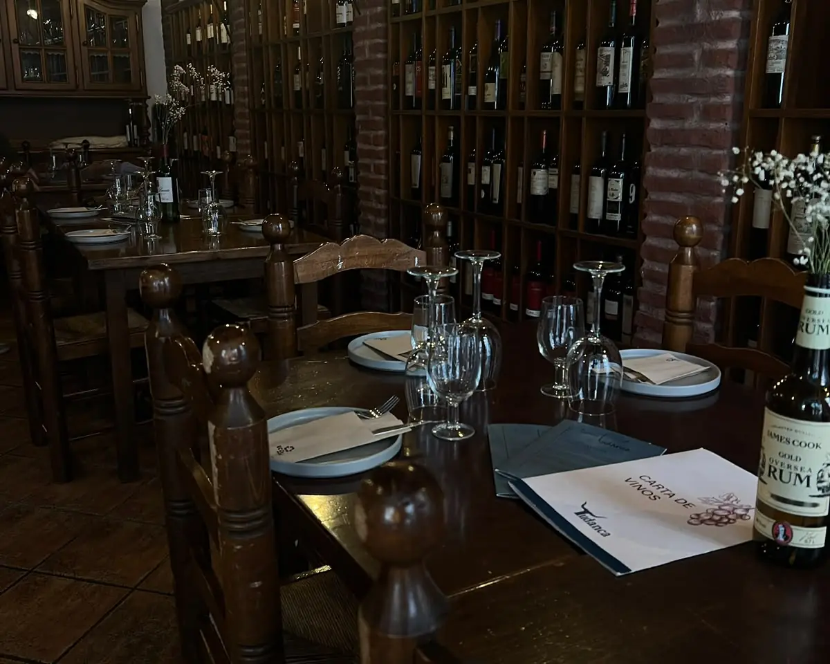 Comedor de Tudanca: mesas de madera junto a la vinoteca con arcos de ladrillo